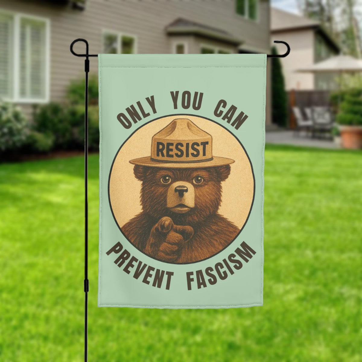 Garden flag with bear wearing a hat and text 'Only you can resist prevent fascism' on a green background.