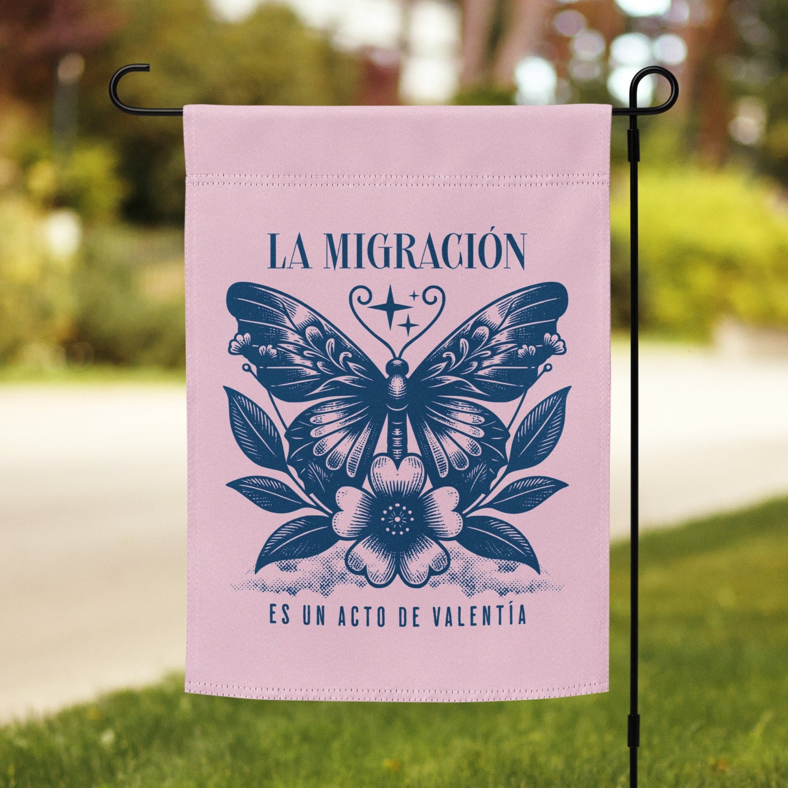 Pink garden flag with butterfly design and text on a grassy lawn